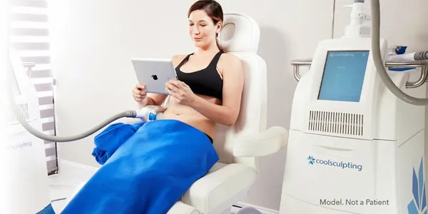 Woman sitting with iPad having CoolSculpting treatment done